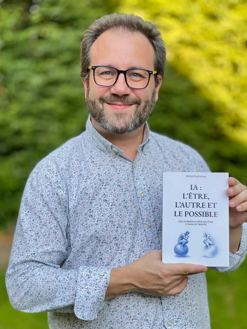 Michel Duchateau tenant son livre IA : l'Être, l'Autre et le Possible